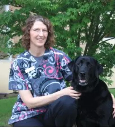 Inger with a black dog at Stuebner Airline Veterinary Hospital